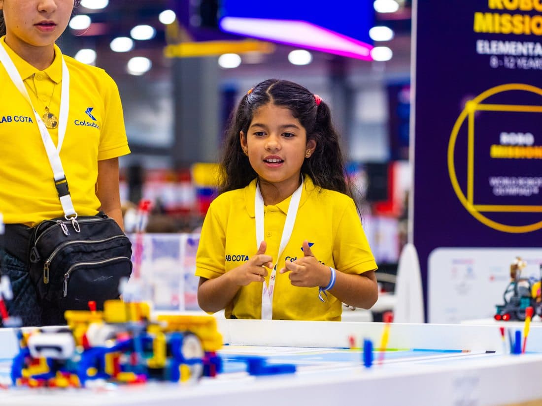 Estudiante en su stand de proyecto robótico