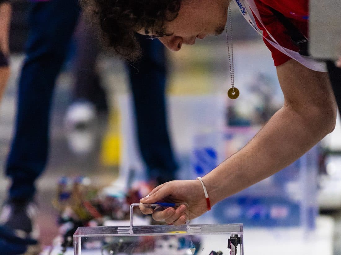 Estudiante ajustando su robot en la mesa de competencia
